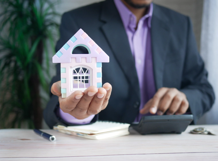 lawyer holding a purple paper house with a calculator and a notebook on the table